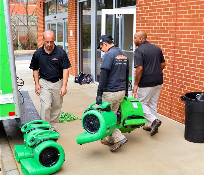 3 SERVPRO technicians carrying air movers for water damage drying