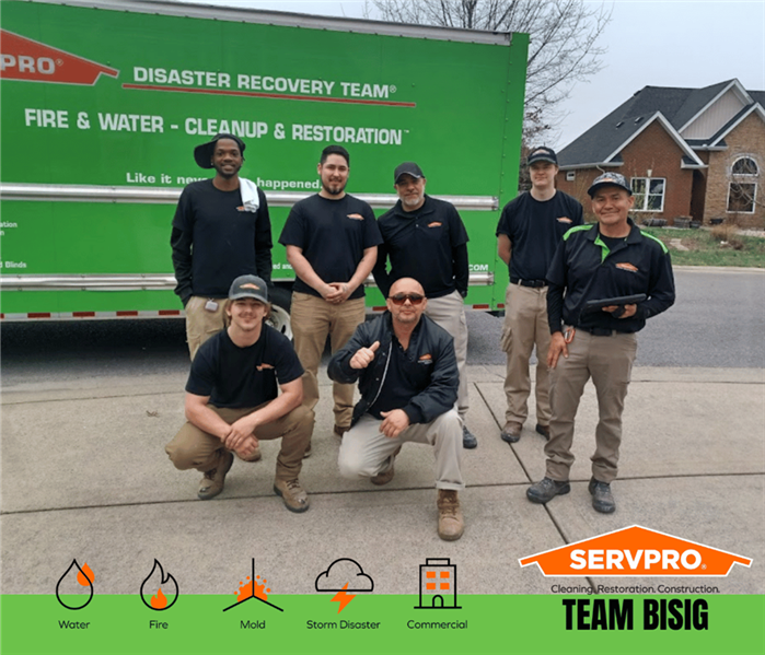 SERVPRO restoration technicians posing in front of a SERVPRO truck after successfully completing a water damage restoration.